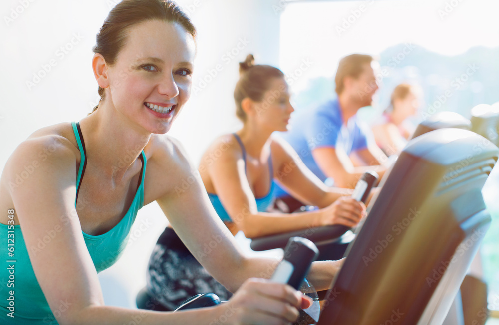 Portrait smiling woman riding exercise bike at gym Portrait smiling woman riding exercise bike at gym
