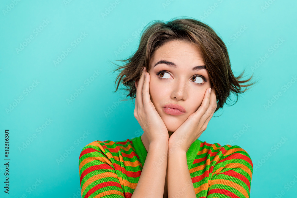Photo of doubtful unsure woman dressed striped t-shirt arms cheeks looking empty space isolated turquoise color background