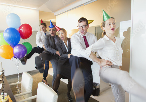 Foto Playful business people with party hats dancing in conga line