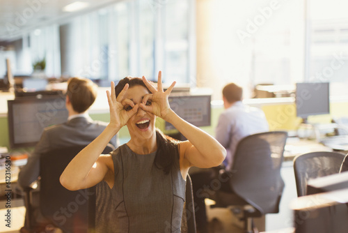 Photos Portrait of playful businesswoman pretending to wear glasses in office