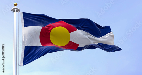 Colorado state flag waving in the wind on a clear day. Three blue, white, and blue stripes. Red C with gold disk on top. 3D illustration render. Fluttering fabric. Selective focus photo