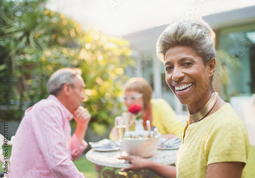 Portrait smiling mature woman enjoying lunch with friends in garden