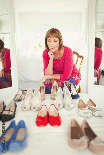 Canvas Print Indecisive mature woman deciding which shoes to wear in closet