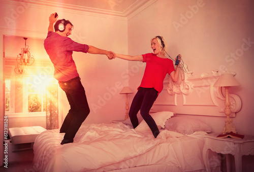 Playful couple dancing on bed listening to music mp3 players headphones photo