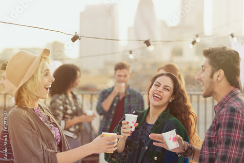 Young adult friends laughing and drinking at rooftop party