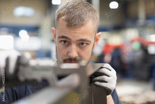 Focused worker examining part in steel factory