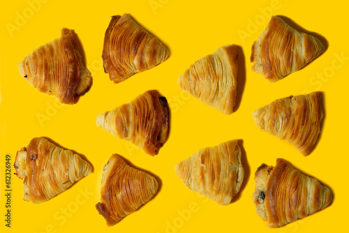 Puff pastry in the shape of a shell Sfogliatelle- traditional Neapolitan sweets made of puff pastry with a filling of sweet ricotta cheese. Italian desserts on a bright yellow background. tasty.banner © Viktorya 