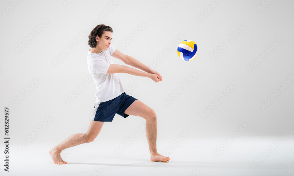 A young volleyball player is training with a ball on a white background. Action, sport, health, team, fitness concept A young volleyball player is training with a ball on a white background. Action, sport, health, team, fitness concept