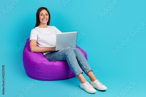 Photo of pretty young girl hold computer smile sit bean chair isolated over blue color background