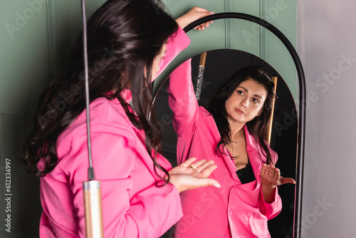 The girl is rehearsing a speech, talking to herself in the mirror.