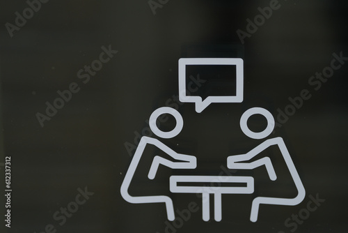 sign with two people sitting at the table talking. detail.