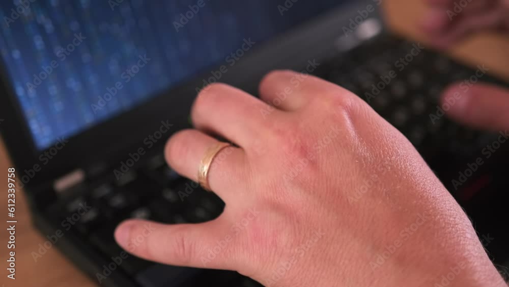 Matrix code on laptop screen, close-up male hands, with wedding ring on finger, typing program code on laptop. Freelancer and work at home concept. Matrix code on laptop screen, close-up male hands, with wedding ring on finger, typing program code on laptop. Freelancer and work at home concept.