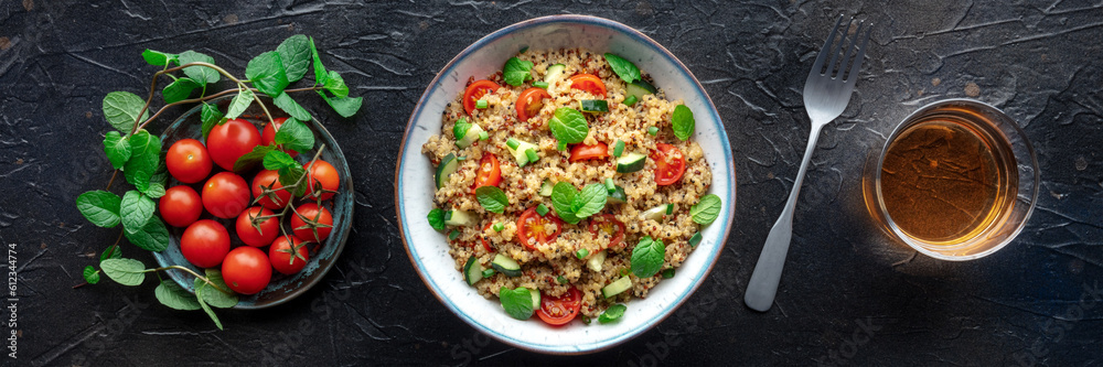 Quinoa tabbouleh salad in a bowl panorama, a healthy dinner with tomatoes and mint, with a drink, overhead flat lay shot