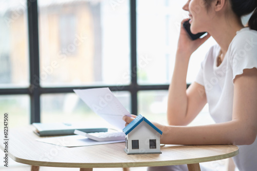 woman sitting on cozy sofa and planning and calculate expense and mortgage with calculator and home on desk  insurance and budget of residential  loan and residence  business and property concept.