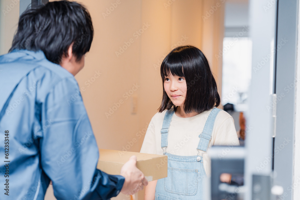 家で宅配便を受け取る小学生の女の子 家で宅配便を受け取る小学生の女の子
