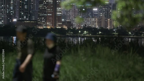Night stroll in Hangang Park with blurred couple and illuminated Seoul skyline across river