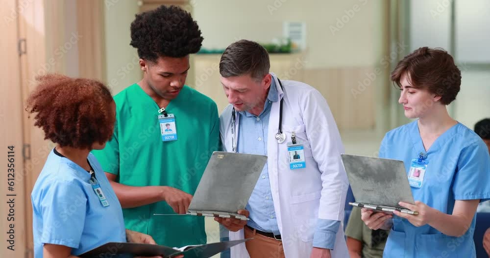 Diverse group of young students doctors standing together and consulting caucasian teacher doctor in a hospital corridor. Medicine medical and health care concept
