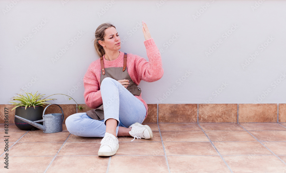 pretty young woman gardering and sitting on the floor outdoors pretty young woman gardering and sitting on the floor outdoors