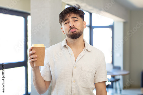 young handsome man feeling sad and whiney with an unhappy look and crying. take away coffee concept © kues1