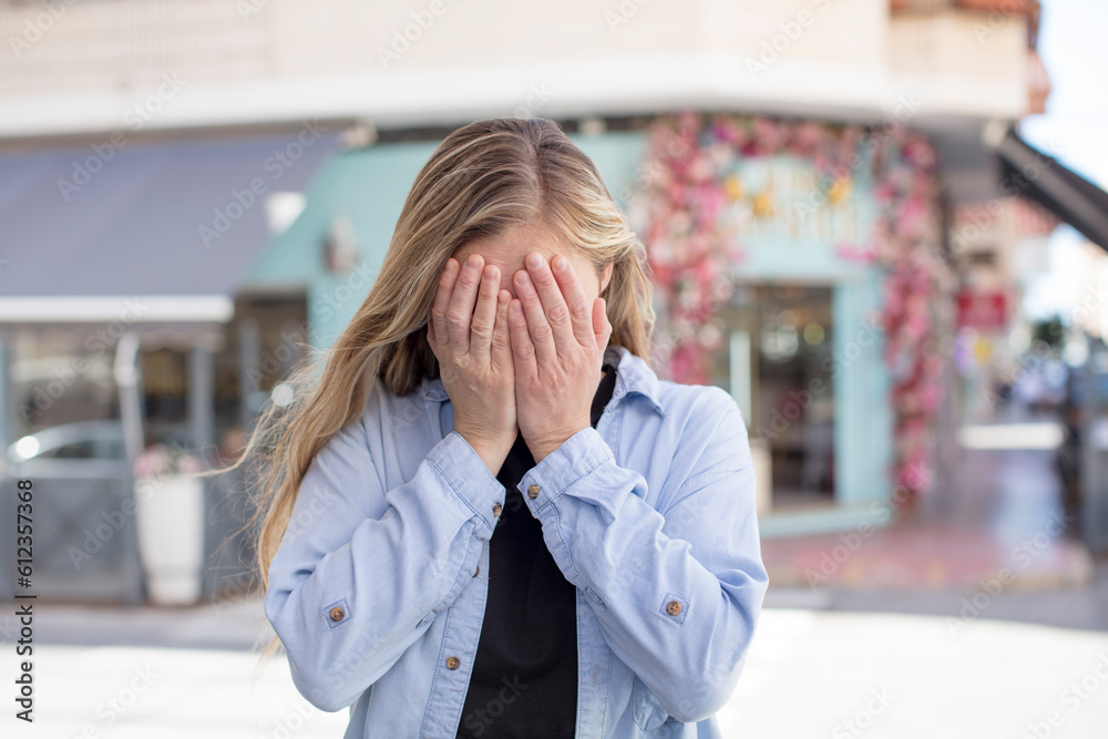 pretty woman feeling sad, frustrated, nervous and depressed, covering face with both hands, crying