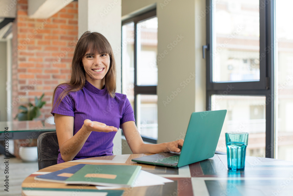 young pretty woman smiling cheerfully, feeling happy and showing a concept.  universitary student with a laptop