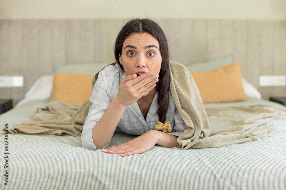 pretty young model covering mouth with a hand and shocked or surprised expression. rest and nightwear concept pretty young model covering mouth with a hand and shocked or surprised expression. rest and nightwear concept