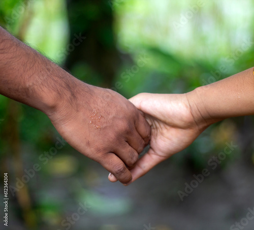 Two friends are hand-shaking, one with white hands and the other with black hands. © Rokonuzzamnan