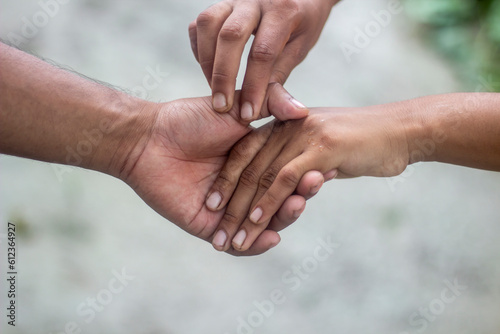 Tow friends are hand shaking, one with white hands and the other with black hands.