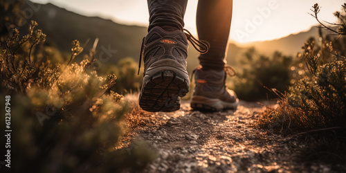 Man hiking up a mountain trail with a close-up of his leather hiking boots. The hiker shown in motion, with one foot lifted off the ground and the other planted on the mountain trail. Generative AI photo