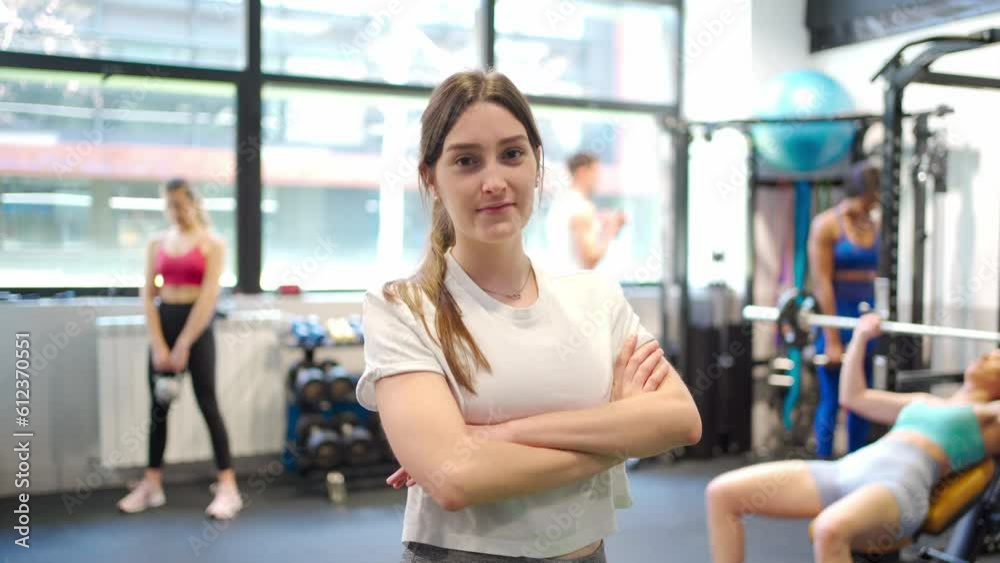 Confident Young Woman Poses, Smiles, and Flexes Her Muscles for the Camera in the Gymnasium Confident Young Woman Poses, Smiles, and Flexes Her Muscles for the Camera in the Gymnasium