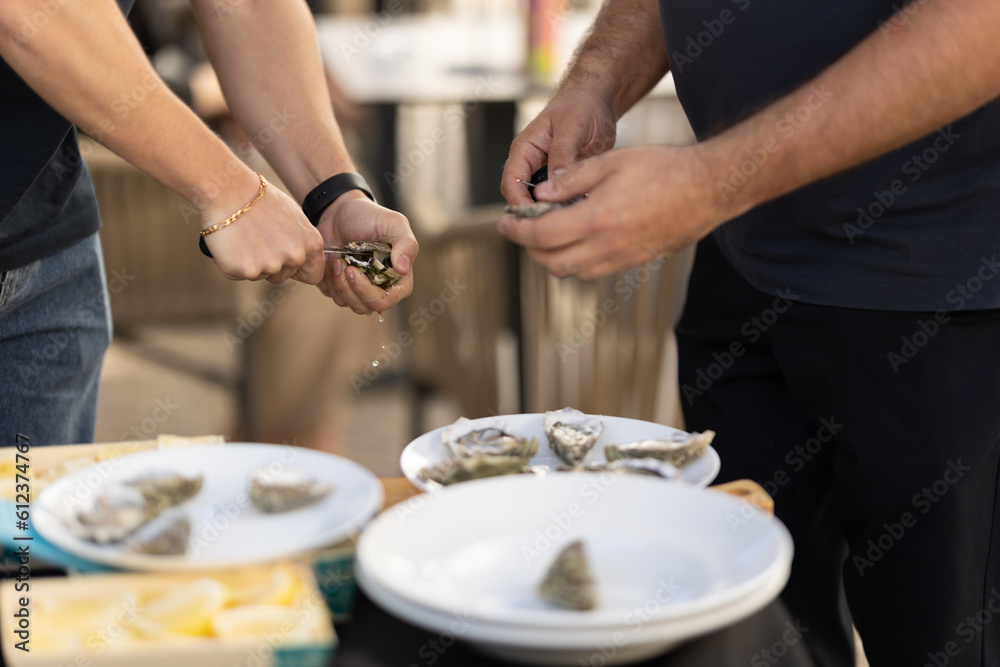 Two men open oysters with a knife