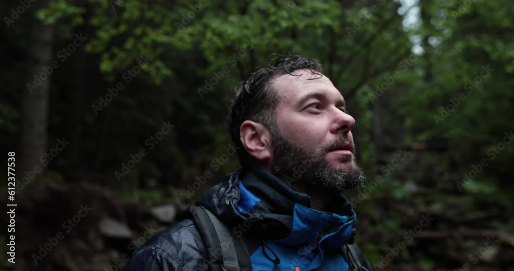 Portrait of a male tourist who stands under the pouring rain on the street and gets wet, looking to the sides. Slow motion shot Portrait of a male tourist who stands under the pouring rain on the street and gets wet, looking to the sides. Slow motion shot