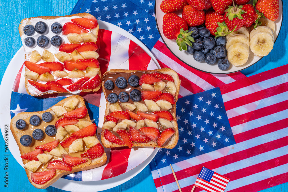 Obraz premium July 4 breakfast sandwiches, holiday snack or brunch with peanut butter, chocolate and cheese spread, with strawberries, blueberries and banana in the shape of america patriotic flag