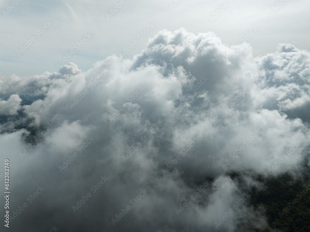 Obraz premium Aerial view of flowing fog waves on mountain tropical rainforest,Bird eye view image over the clouds Amazing nature background with clouds and mountain peaks in Thailand