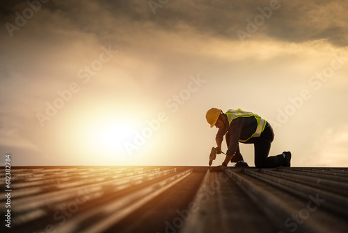 Worker repairing the roof on a construction site. Electric drill used on roof, Roof construction concept.