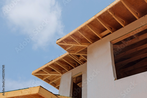 There are wooden beams rafters planks along corner of house that are attached to eaves