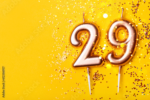 29 years celebration. Greeting banner. Gold candles in the form of number twenty nine on yellow background with confetti. photo