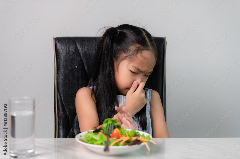 Little asian cute girl refuses to eat healthy vegetables.Nutrition & healthy eating habits for kids concept.Children do not like to eat vegetables. Little asian cute girl refuses to eat healthy vegetables.Nutrition & healthy eating habits for kids concept.Children do not like to eat vegetables.