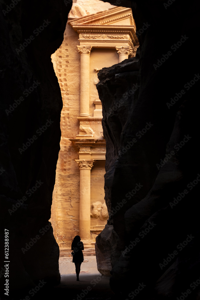 Silhouette of a woman in front of the beautiful Al Khazneh (The Treasury) seen through of a canyon's walls in Petra. Petra is a historical and archaeological city in southern Jordan