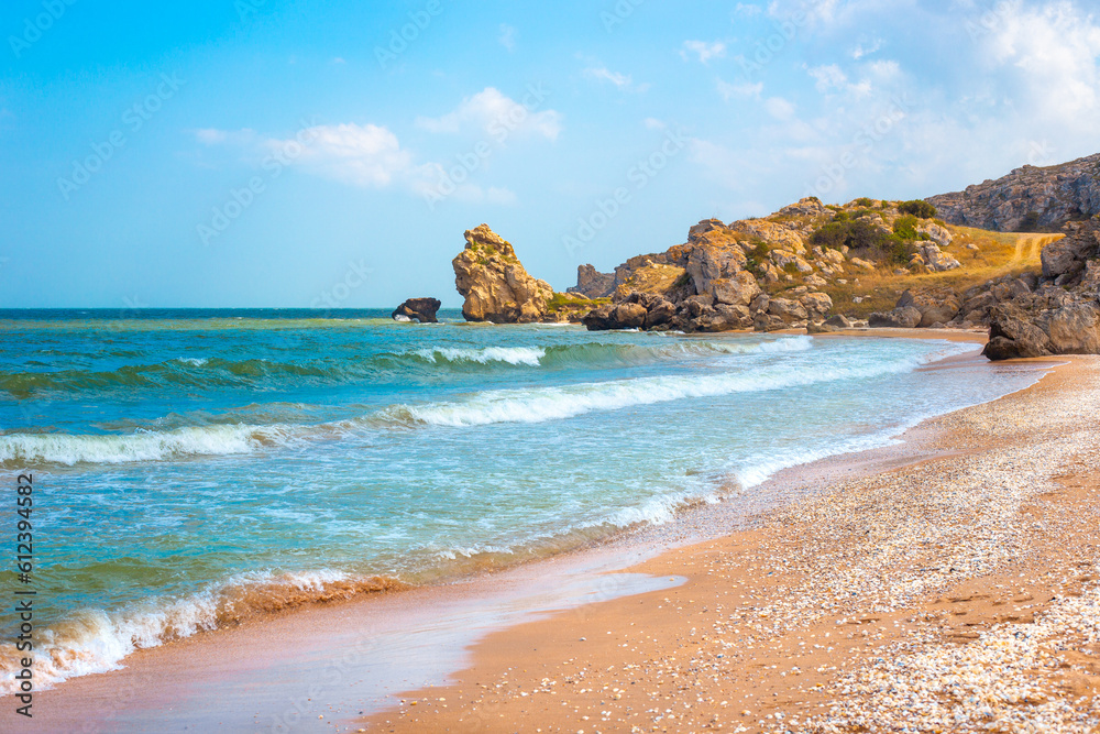 Seascape. Blue sea and rocky shore with yellow sandy beach. Sea of Azov in Crimea