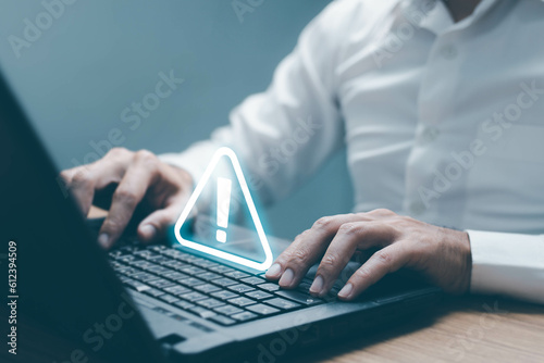 Businessman using computer laptop with triangle caution warning sing for notification error and maintenance concept.