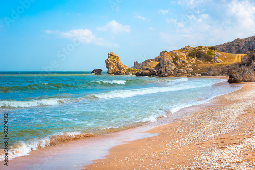 Seascape. Blue sea and rocky shore with yellow sandy beach. Sea of Azov in Crimea