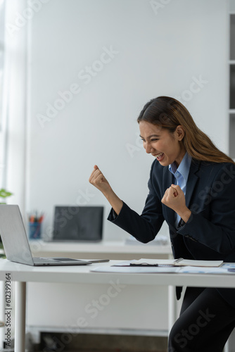 Confident Asian businesswoman smiling happy expression While using a laptop at work to start a successful small business and thrive financially.