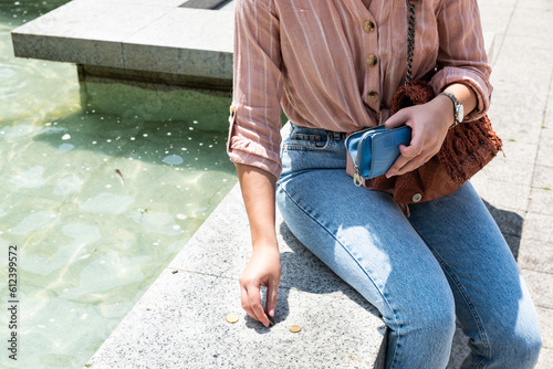 Fotografia Young woman tourist collecting coins for wishing well of fountain