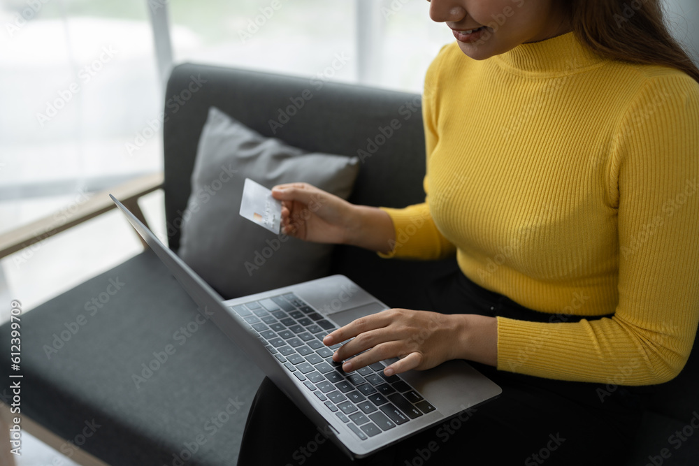 Naklejka premium Business woman, young woman holding credit card and using laptop computer for online shopping, e-commerce, banking, internet application, spending money, working from home startup business ideas