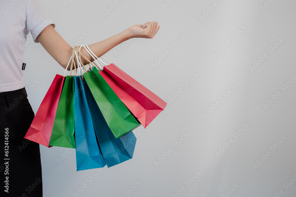 Portrait of beautiful smiling Asian woman in white shirt holding shopping bags posing on white background.
