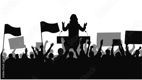 Woman standing in the crowd giving a presentation. Crowd people flags, banners. 