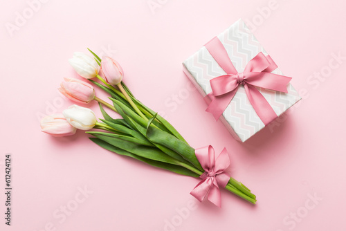 Pink tulips flowers and gift or present box on colored table background. Mothers Day, Birthday, Womens Day, celebration concept. Space for text top view © sosiukin