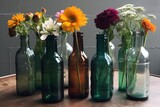A collection of colorful flowers arranged in upcycled bottles used as decorative vases.