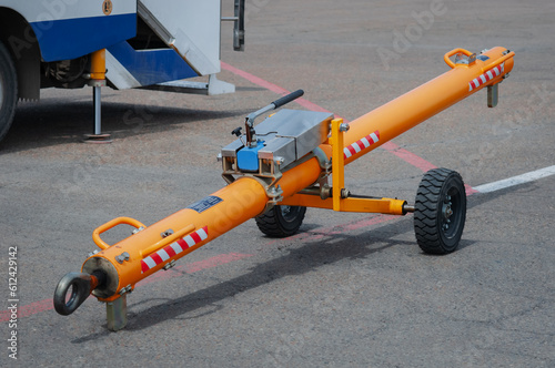 Towing carrier for aircraft on the apron of the airfield. Special equipment for the transportation of air transport. An orange pipe with wheels with a built-in shock absorber on the pavement close up.